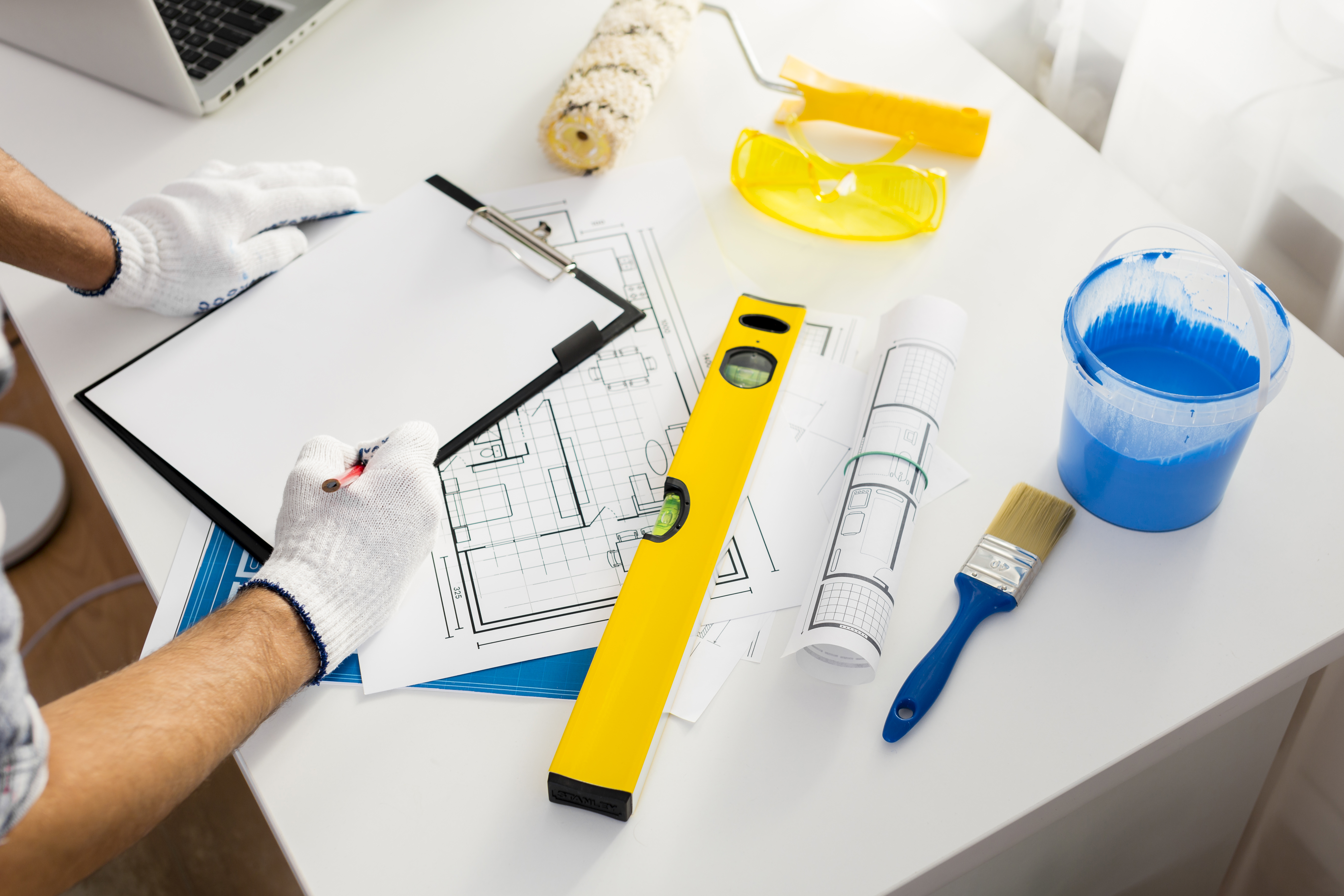 Architekturplanung und Malerutensilien auf Tisch.